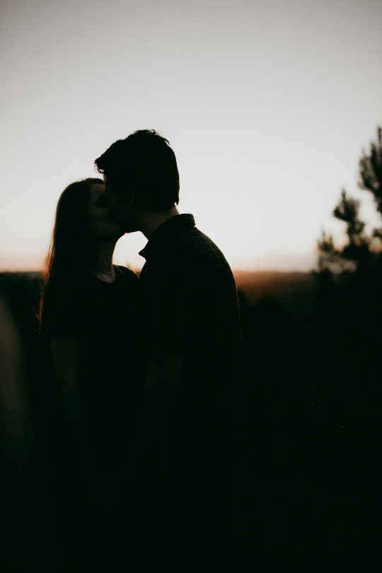 Couple shares a kiss as the sun sets.