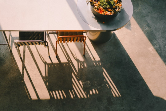 Tables, chairs, and shadows creating a sunny scene.