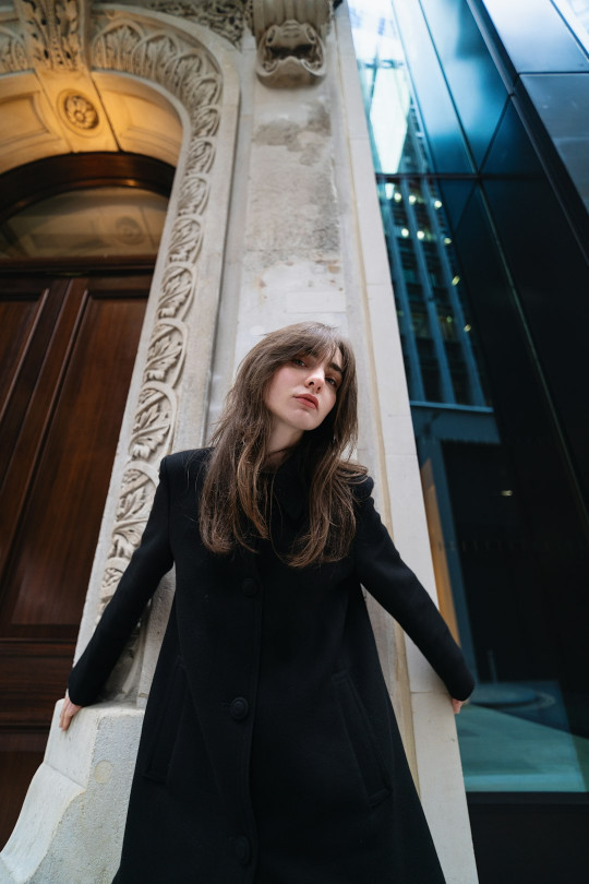 A woman in a black dress standing in front of a building