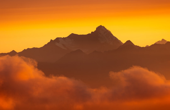 A plane flying over a mountain covered in clouds