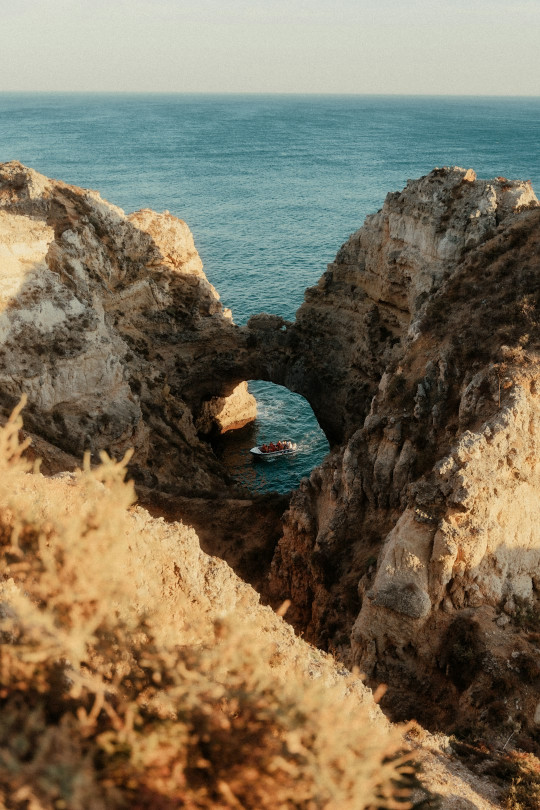 A man standing on top of a cliff next to the ocean