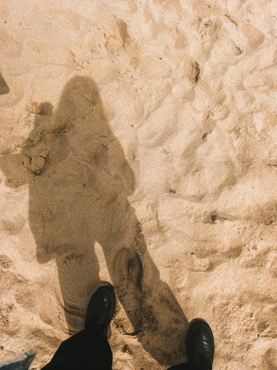 A shadow of a person standing in the sand