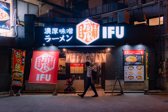 A man walking past a restaurant at night