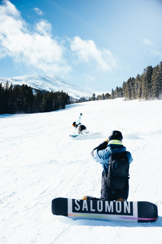 A snowboarder is sitting in the snow on a sunny day