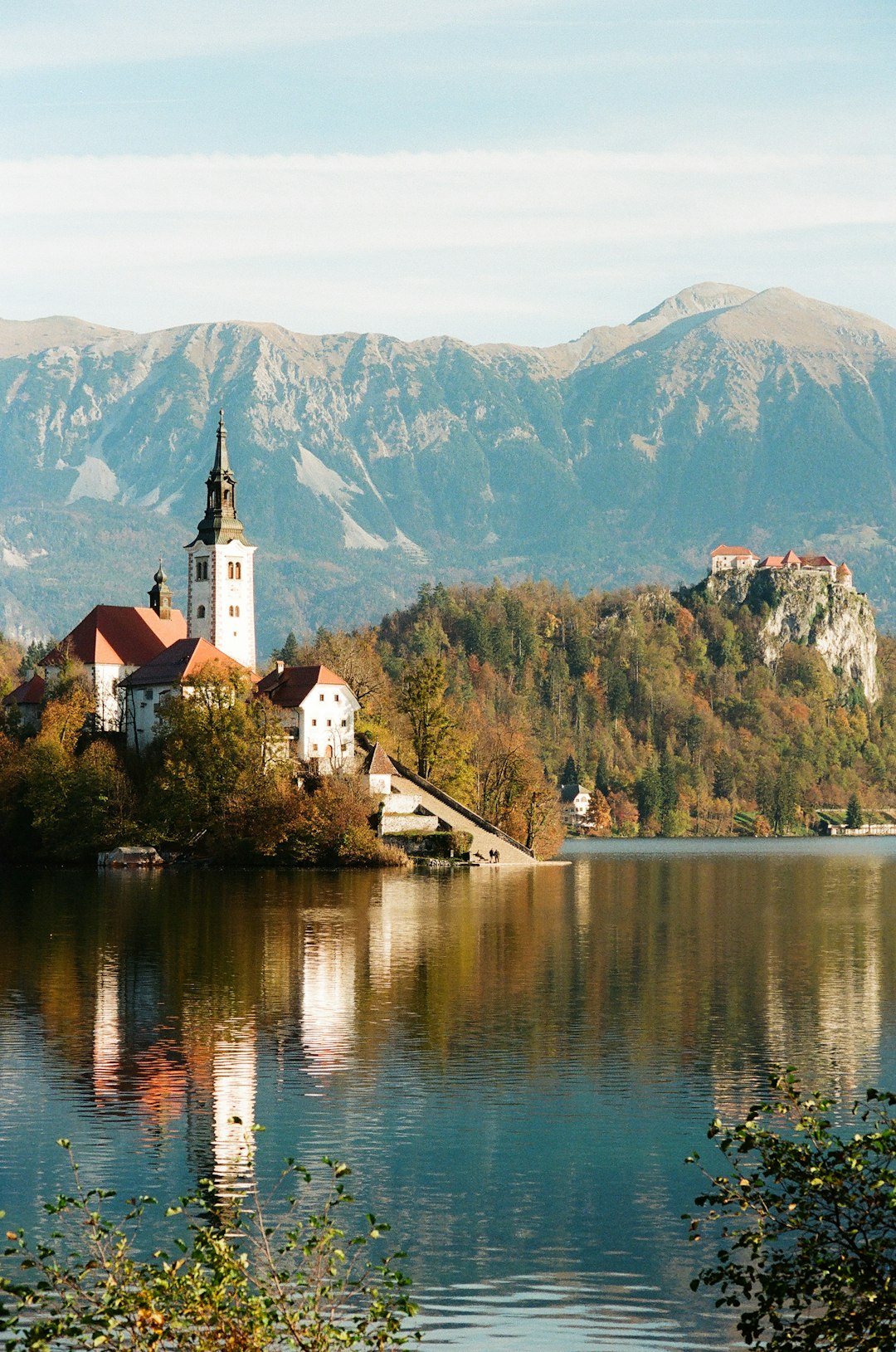 A lake surrounded by mountains with a church in the middle