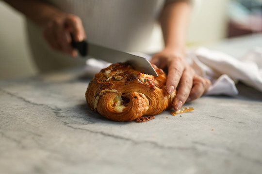 A person cutting a piece of bread with a knife