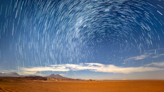 A star filled sky over a desert landscape