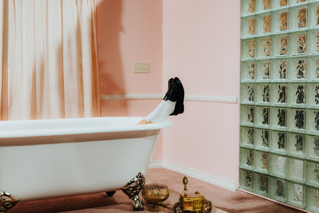 A bathroom with a claw foot tub and a glass block wall