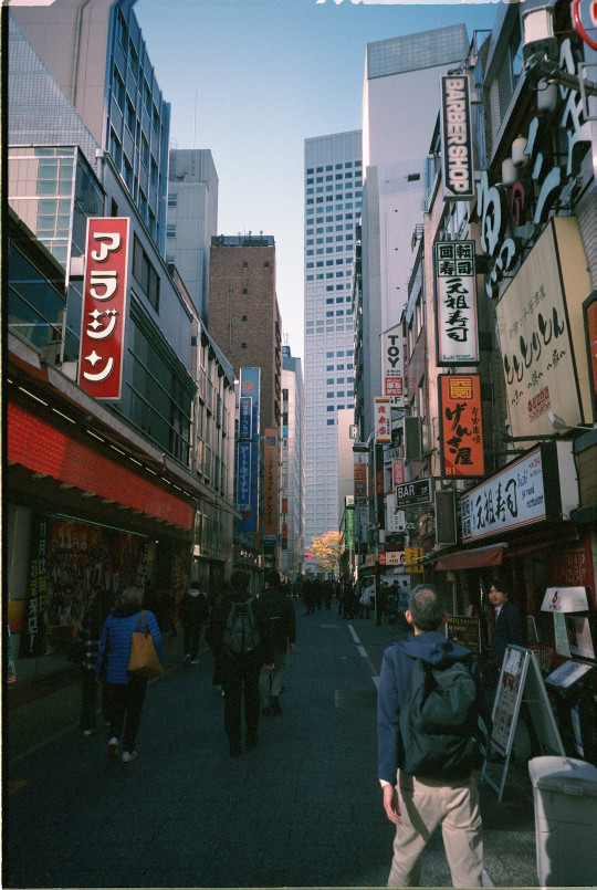 A man walking down a street next to tall buildings