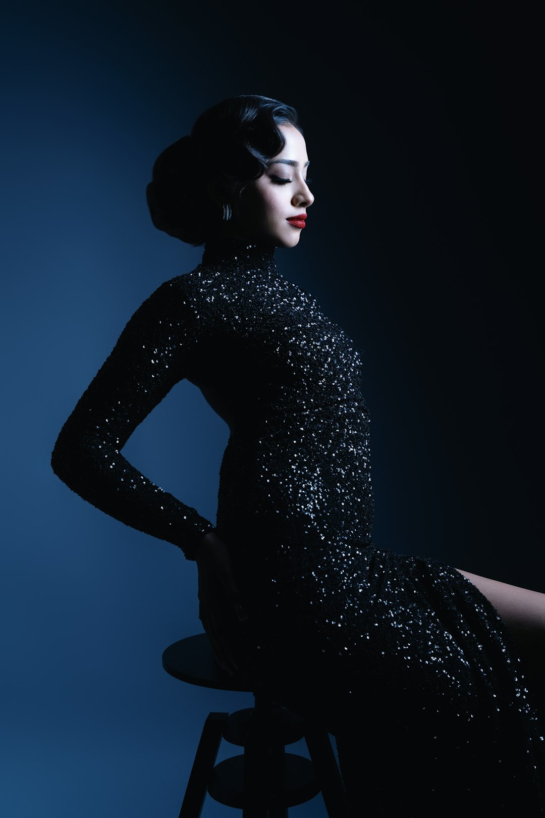 A woman in a black dress sitting on a stool