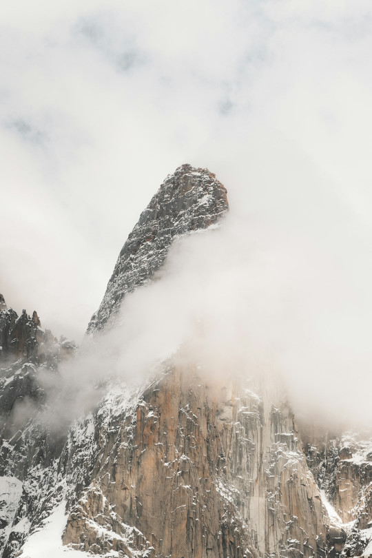 A mountain covered in snow and clouds