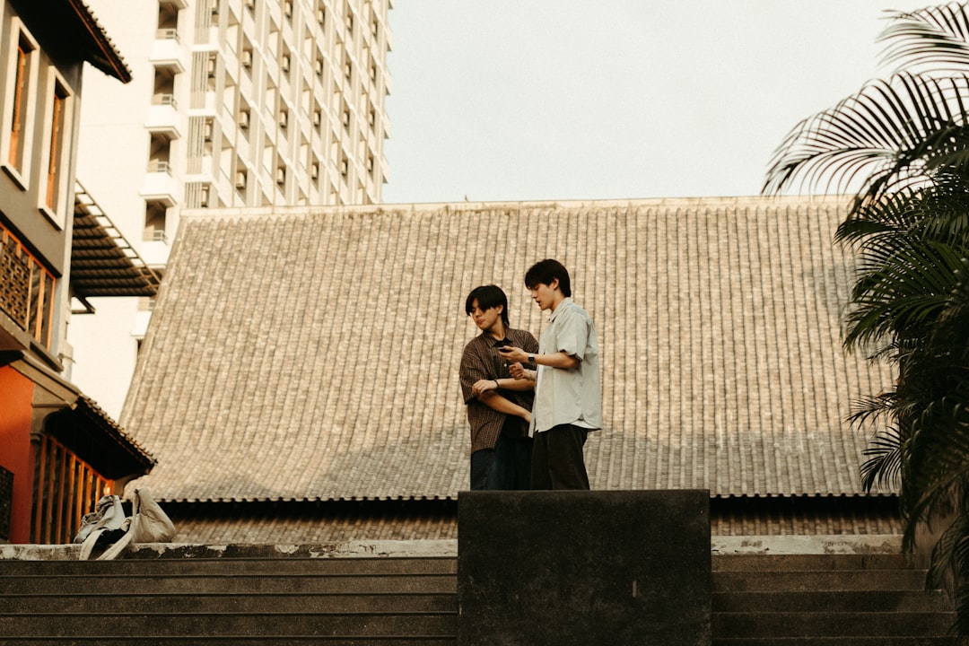 Two boys standing on a roof looking at a cell phone