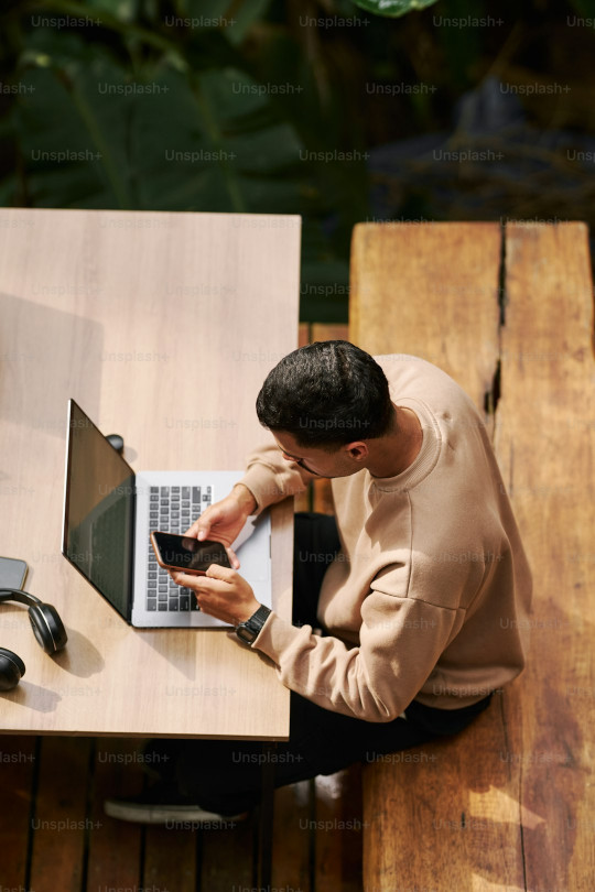 A man sitting at a table using a laptop computer