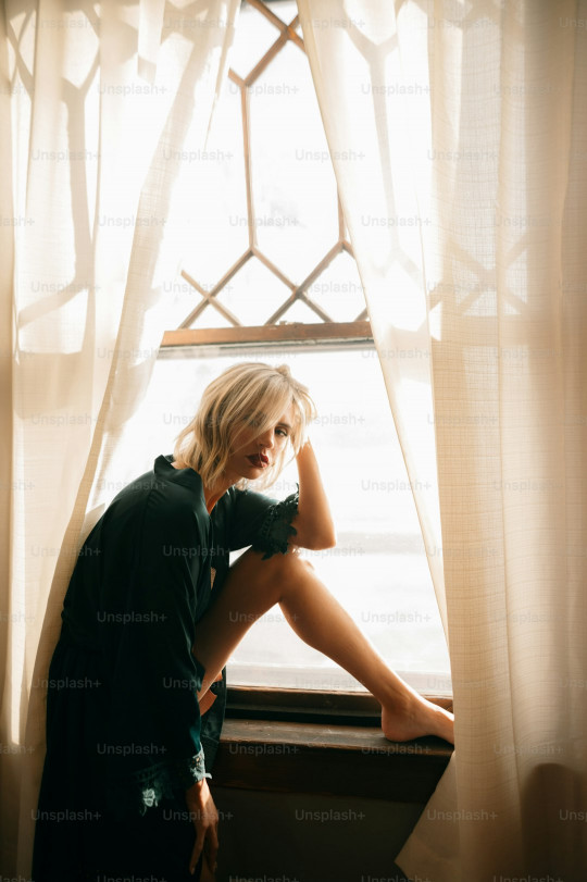 a woman sitting on a window sill in front of a window