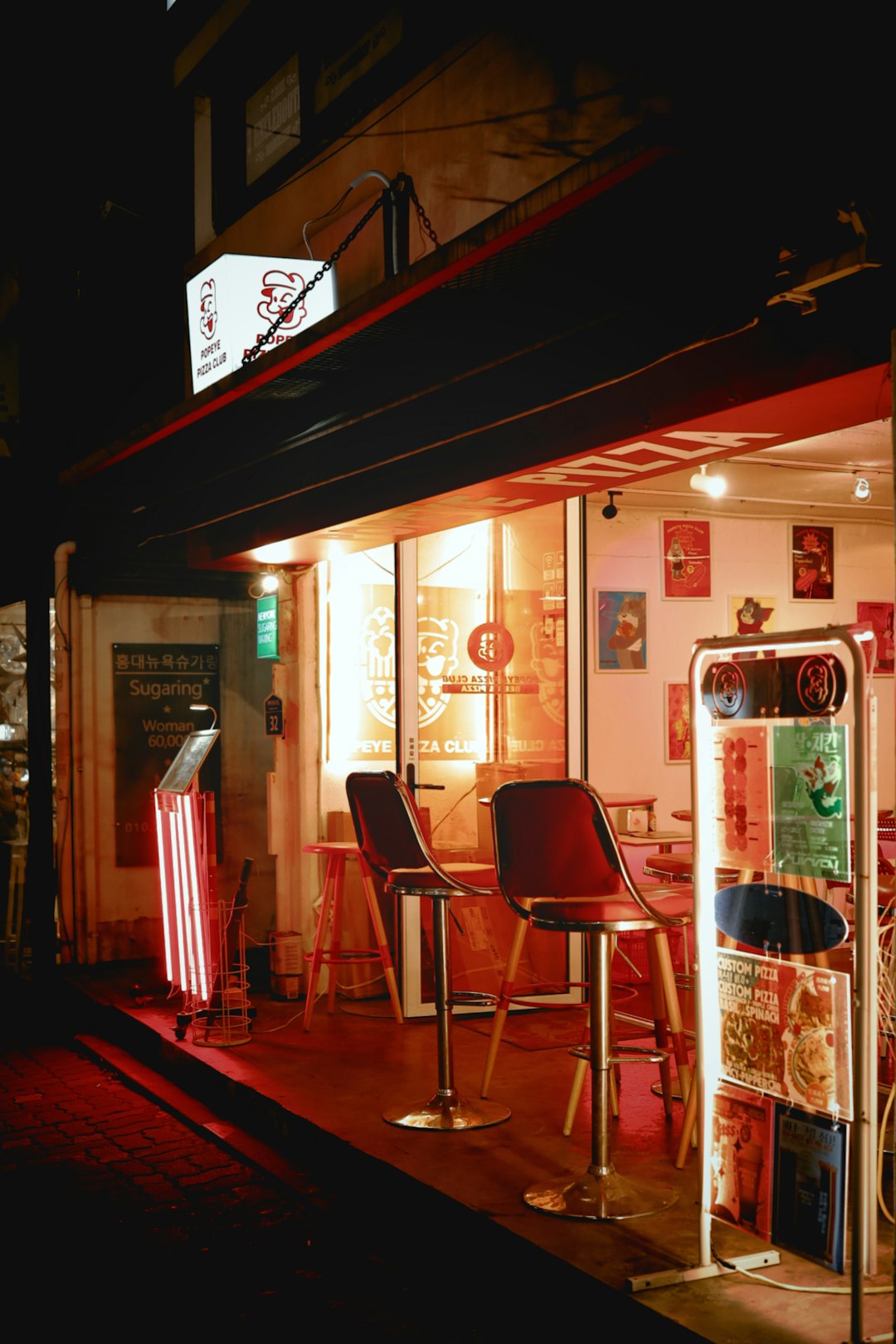 A restaurant at night with chairs and tables outside