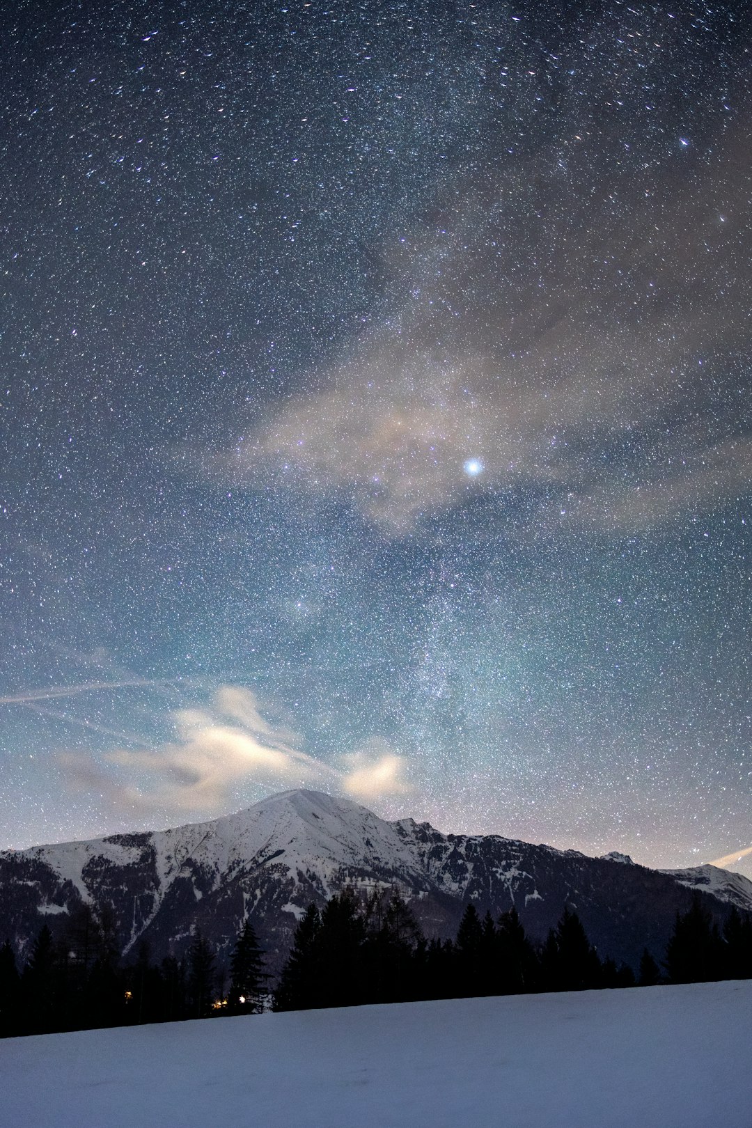 The night sky with stars above a snowy mountain