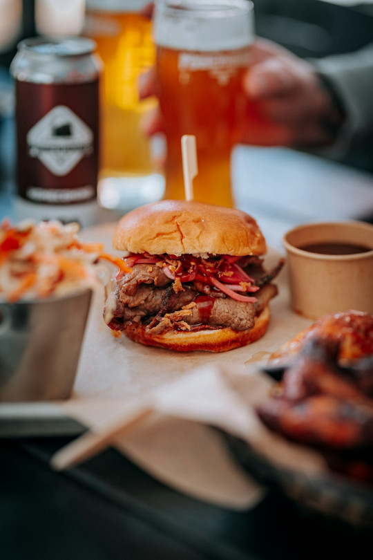 A table topped with a sandwich and two cups of beer