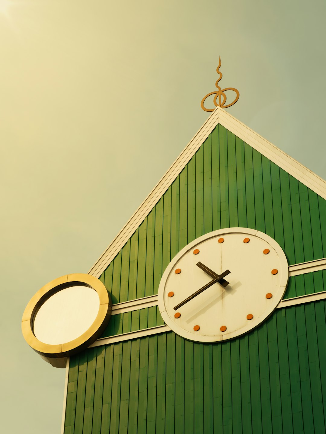 A clock on the side of a green building