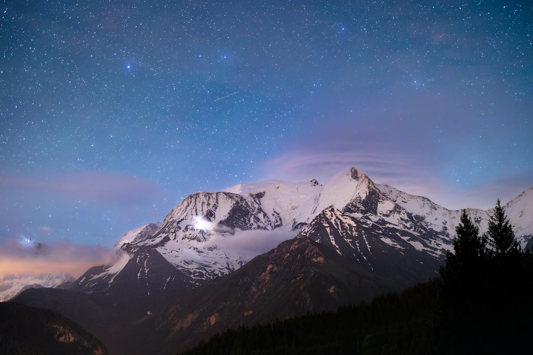 A night sky with stars above a mountain range