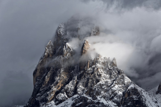 A mountain covered in snow under a cloudy sky