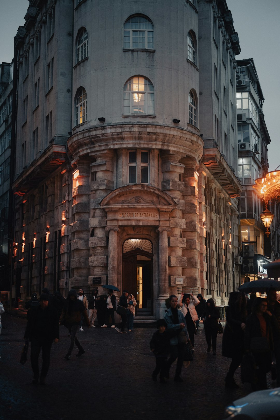 A group of people walking down a street next to tall buildings