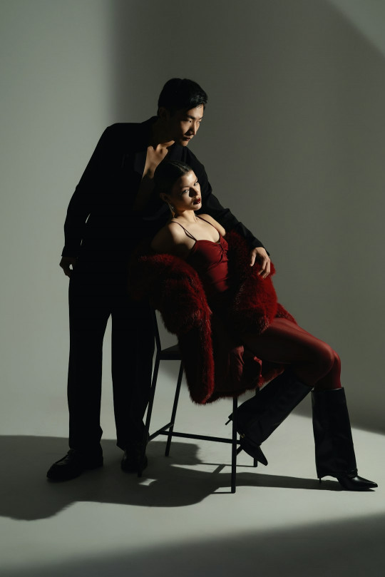 A man standing next to a woman sitting on a chair