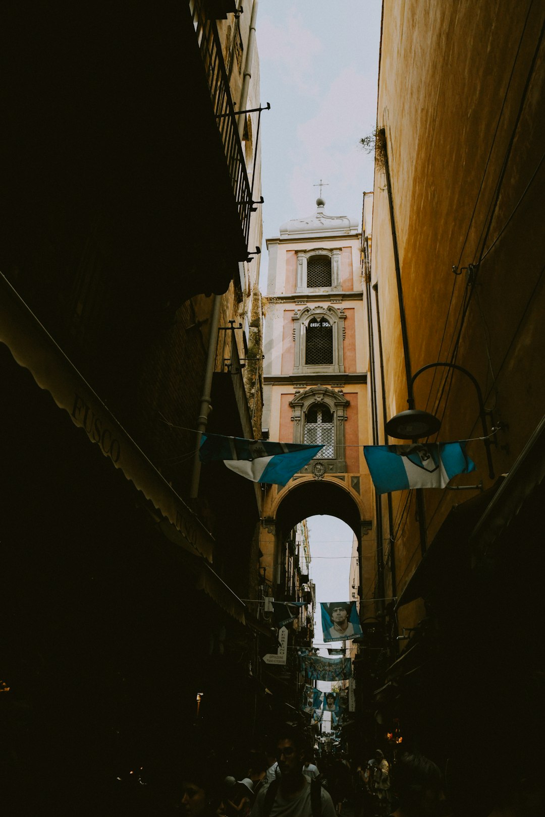 A narrow alleyway with a clock tower in the background