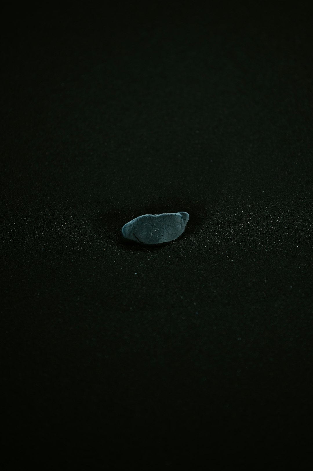 A black surface with a small piece of glass on it