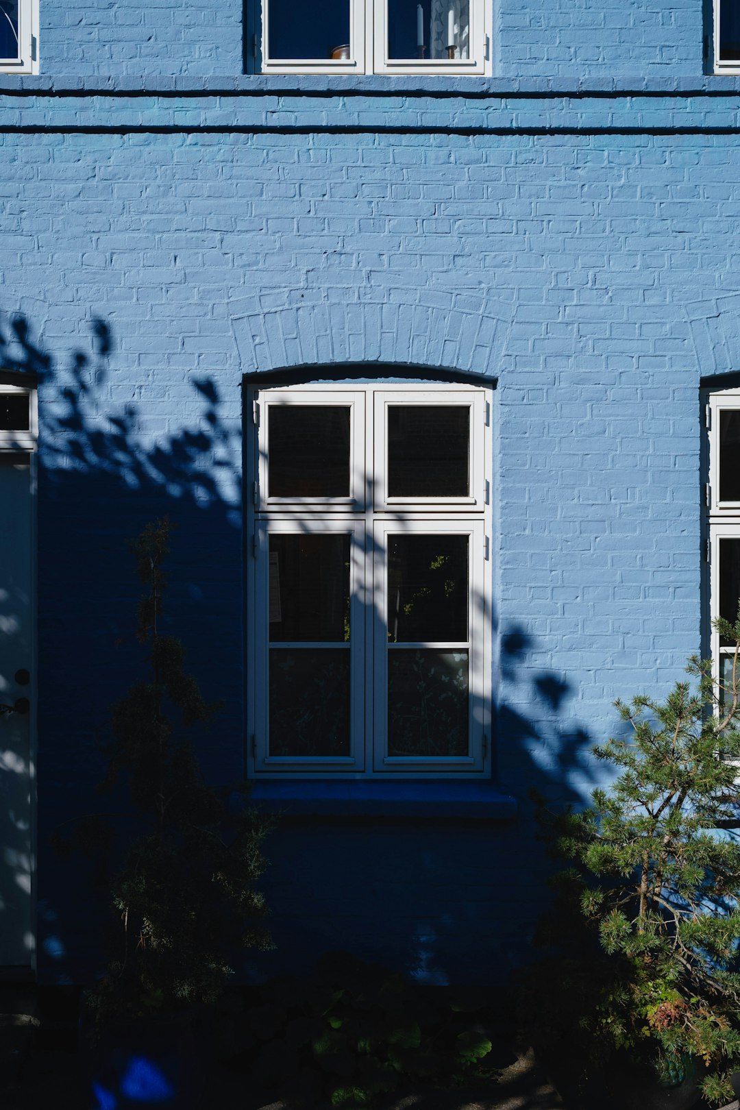 A blue building with three windows and a clock