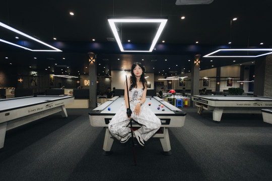 A woman sitting on top of a pool table