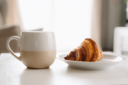 A cup of coffee and a croissant on a table