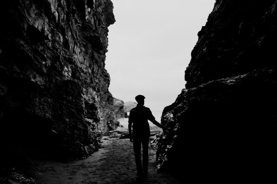 A man walking through a tunnel in a stone wall