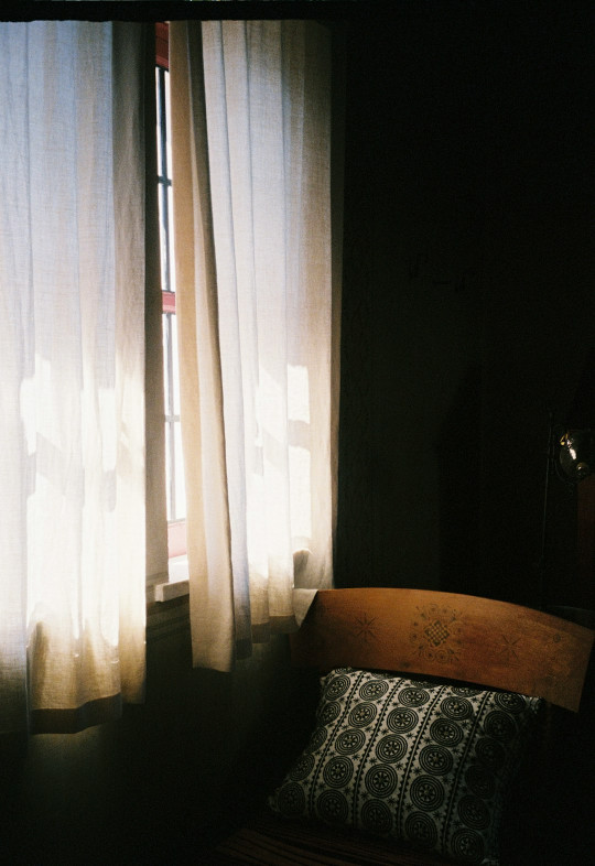 A bed sitting next to a window in a dark room