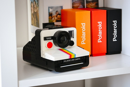 A polaroid camera sitting on top of a white shelf