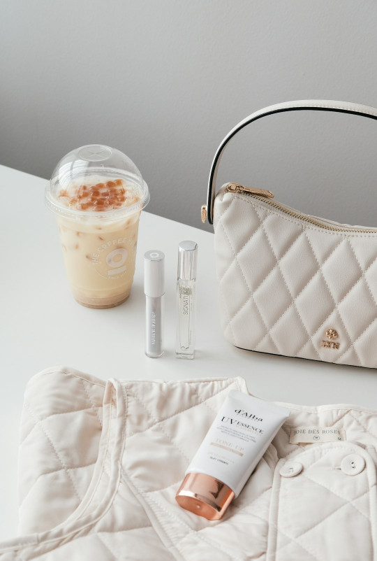 A white purse sitting on top of a table next to a cup of coffee