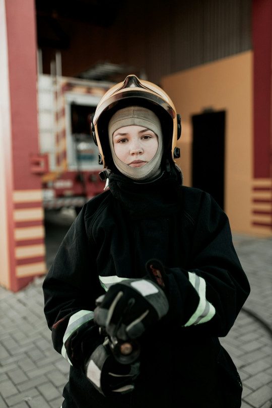 A person wearing a helmet and gloves standing on a sidewalk