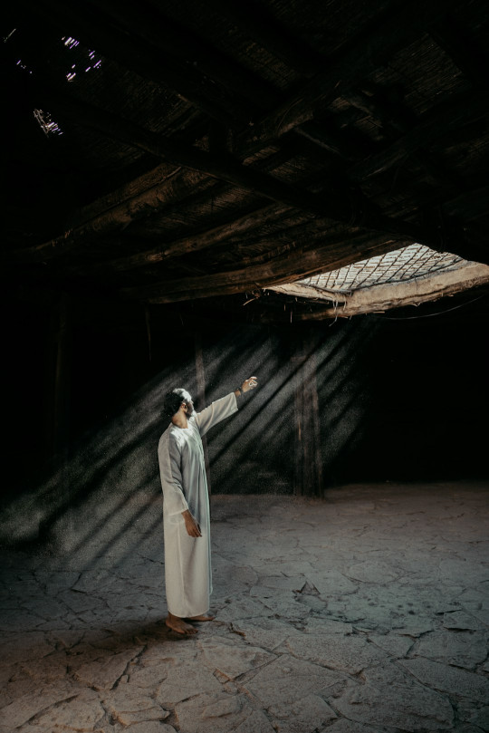 A man standing in a dark room pointing at something