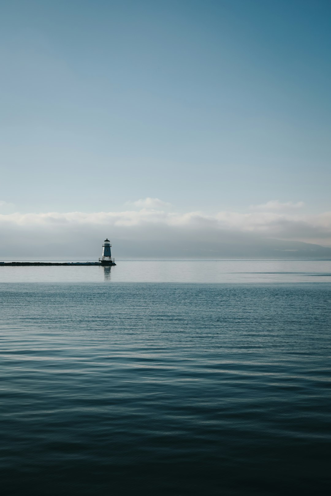 A lighthouse on a small island in the middle of the ocean