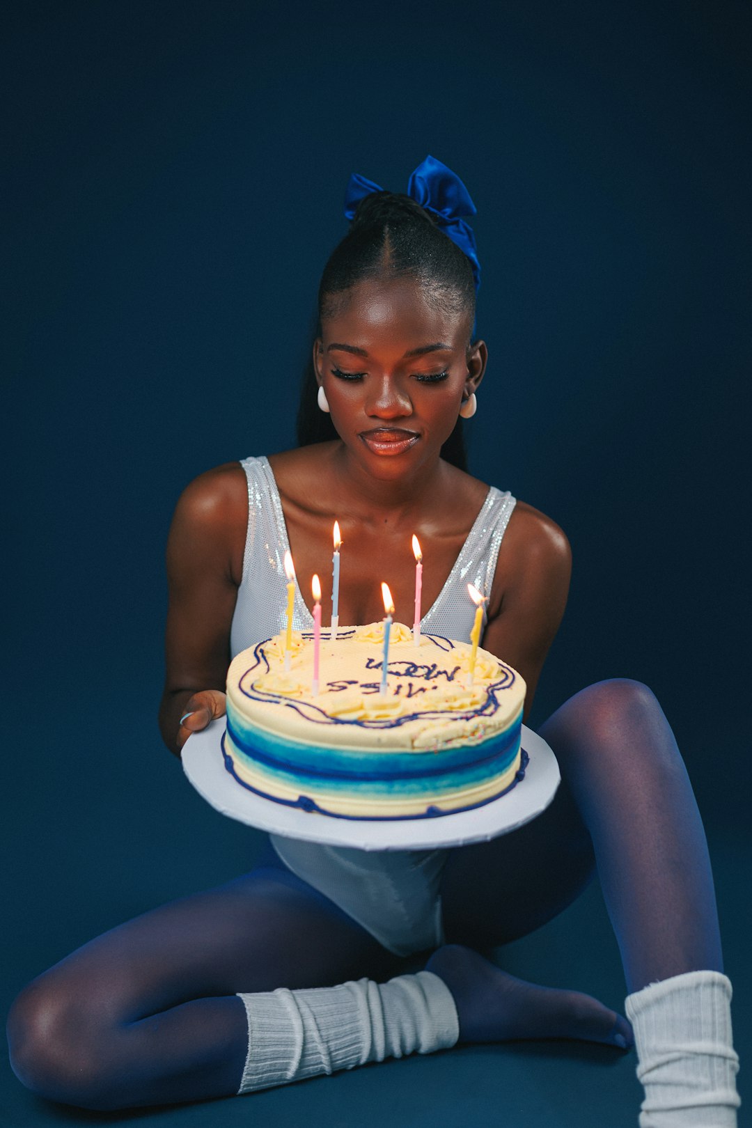 A woman sitting on the floor holding a cake with lit candles