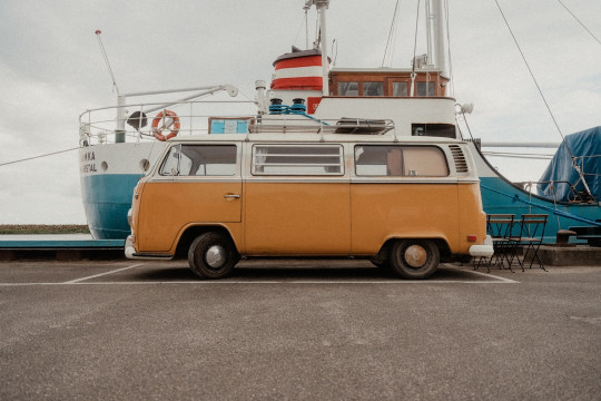 A van parked in a parking lot next to a boat