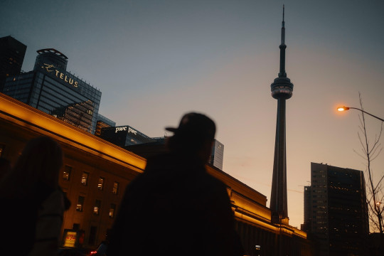 A man walking down a street next to tall buildings