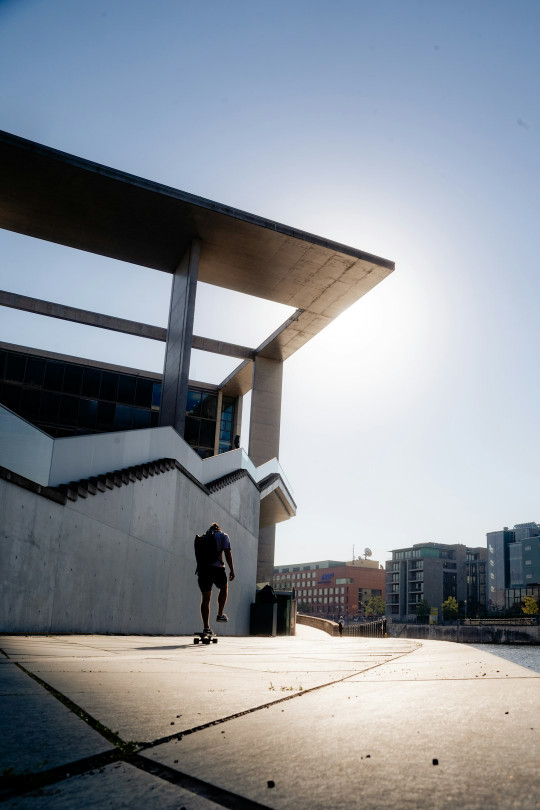 A man riding a skateboard down a sidewalk next to a tall building