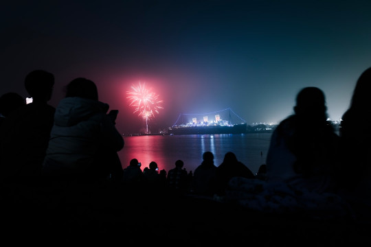 A group of people watching fireworks on the water