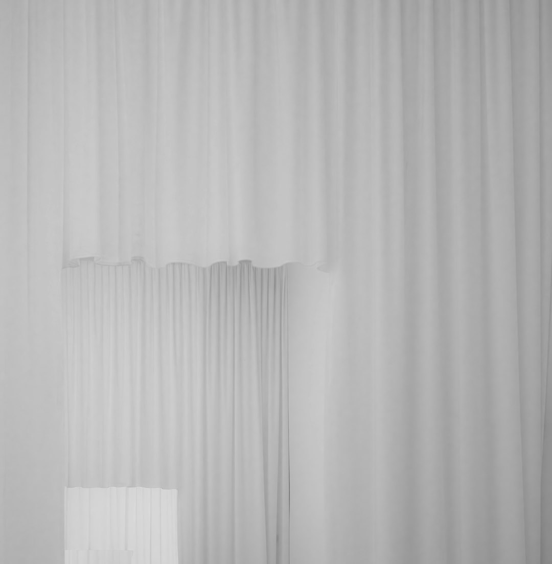 A white chair sitting in front of a white curtain