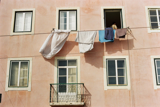 A pink building with clothes hanging out of the windows