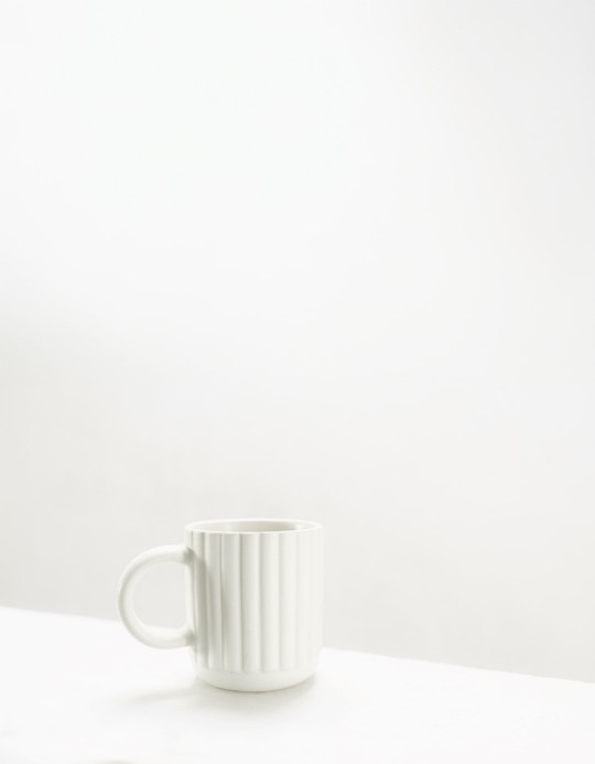 A white cup sitting on top of a white table