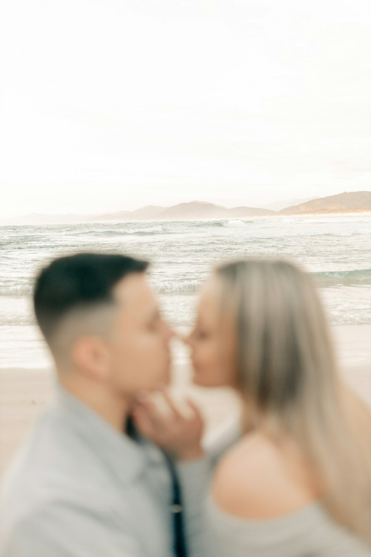 A man and a woman are kissing on the beach