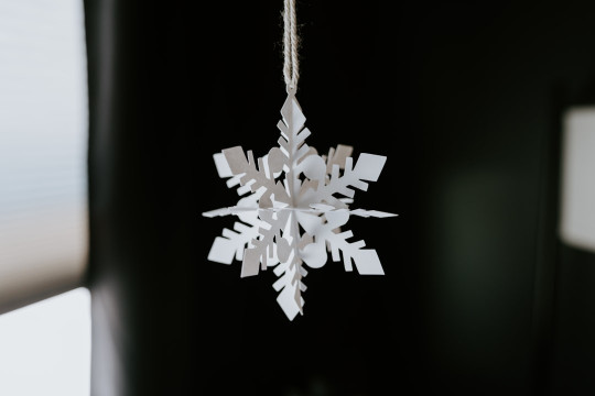 A snowflake ornament hanging from a window