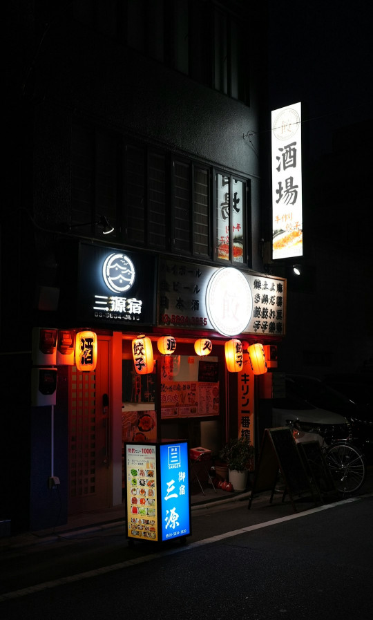 A dark street at night with a restaurant lit up