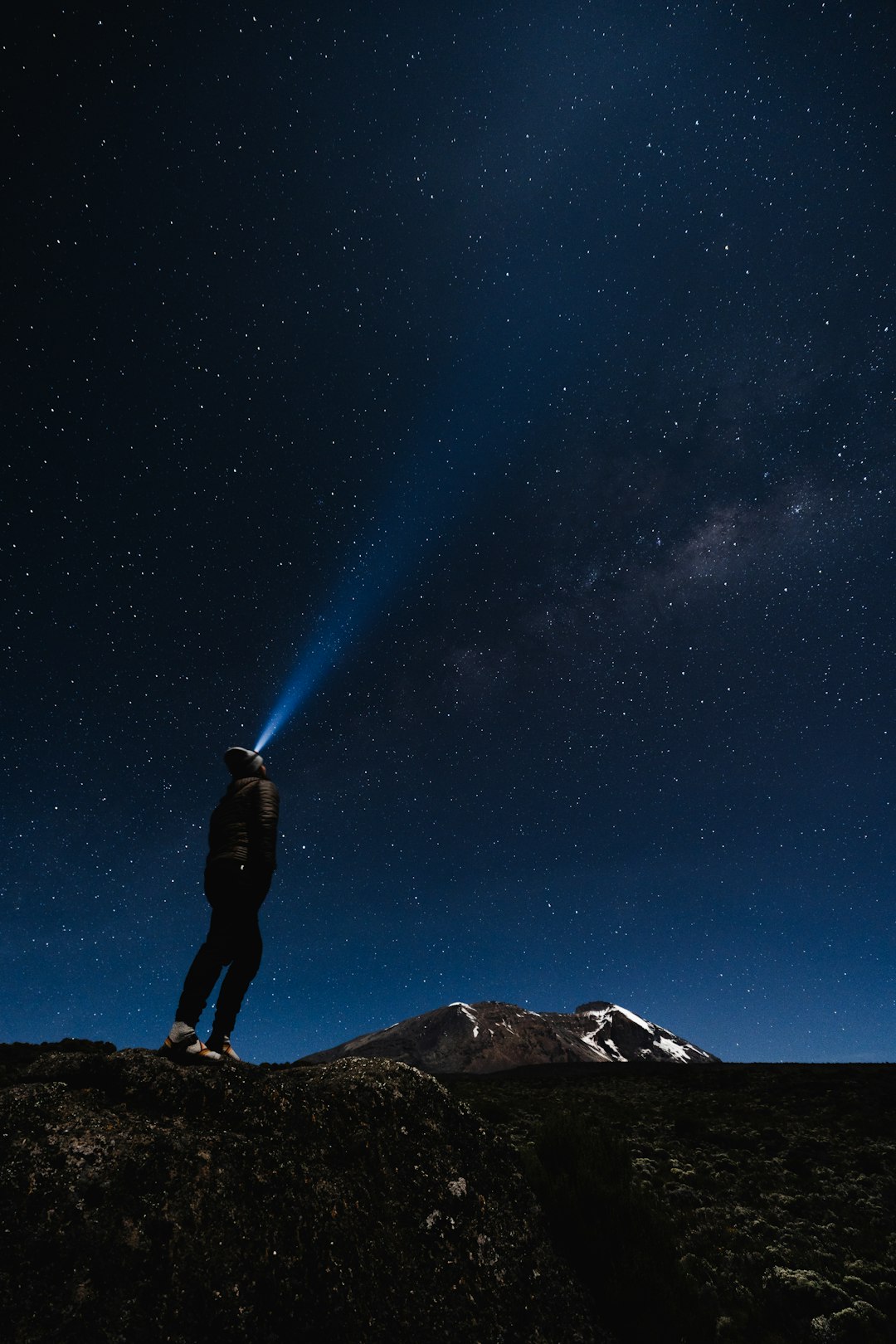 A man standing on top of a mountain under a night sky